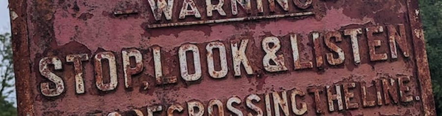 an old railway sign, reading 'Warning, stop look & listen'